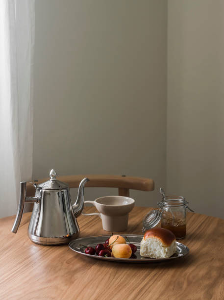 istock Coffee break - bun, fig jam, fruit, cup, metal coffee pot on a round wooden table 2160087756