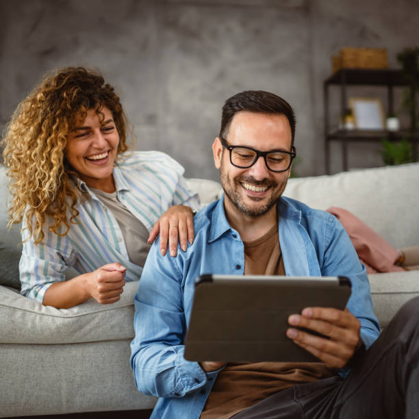 istock Boyfriend sit on the floor use tablet while girlfriend lie and hug him 2160088917