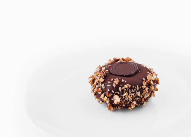 Exquisite chocolate tart topped with nuts and a chocolate disc, isolated on a white backdrop