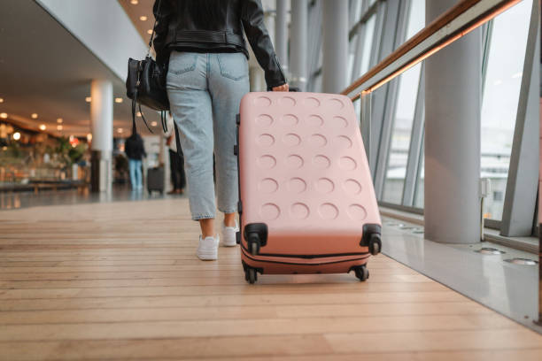 istock Young woman pulling her luggage at the airport 2160091085