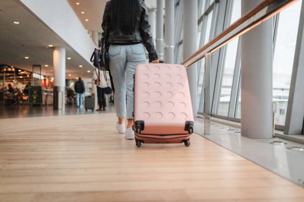 istock Young woman pulling her luggage at the airport 2160091089