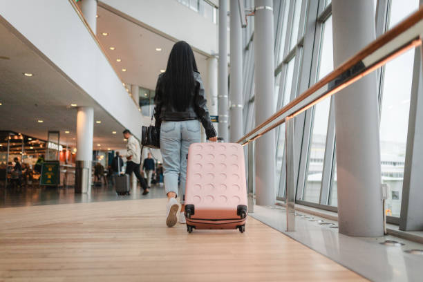 istock Young woman pulling her luggage at the airport 2160091094