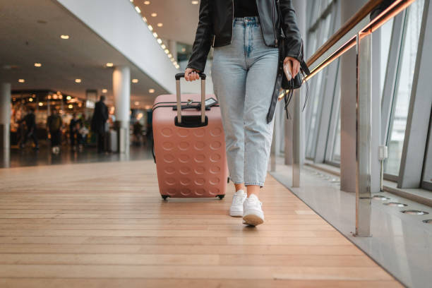 istock Young woman pulling her luggage at the airport 2160091111