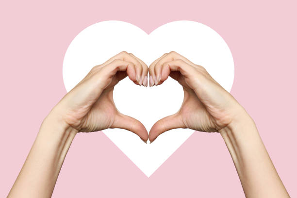 istock Women's hands show a heart-shaped sign on a pink background 2160093978