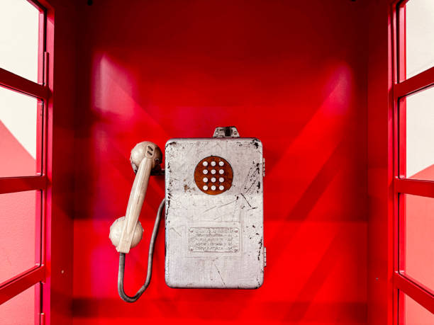 An old-fashioned, rusty red telephone in a vintage booth.