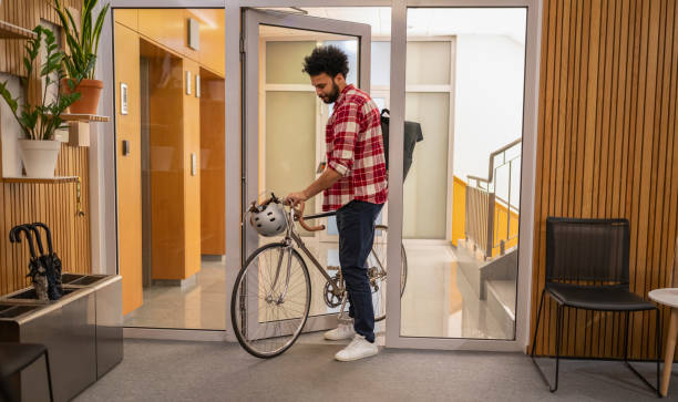 Young businessman entering in office with bicycle. Modern lifestyle and Business concept.