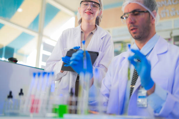 istock scientists perform experiments and record data. people arranges equipment with test tubes and chemicals for producing medicine and biochemistry. man hold tubes of chemical liquids and plant samples. 2160105245