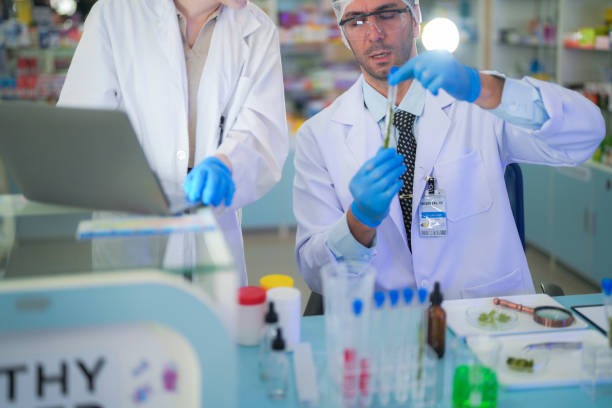istock scientists perform experiments and record data. people arranges equipment with test tubes and chemicals for producing medicine and biochemistry. man hold tubes of chemical liquids and plant samples. 2160105394