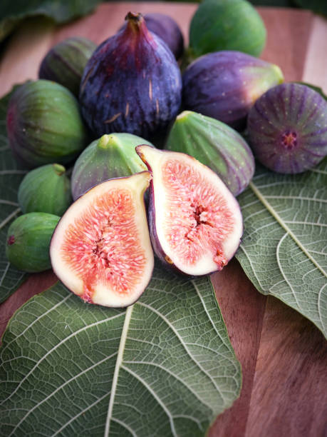 istock Whole and halved figs on wooden surface 2160106317