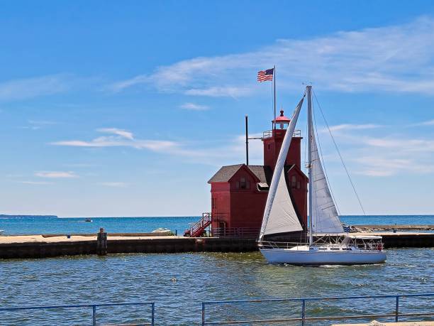 Sailboat sailing past Big Red lighthouse in Holland Michigan harbor