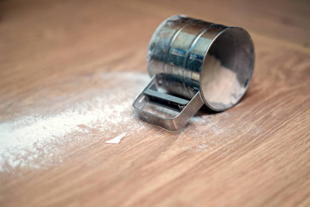 istock tin sieve cup with flour has fallen on the floor, symbolizing a kitchen mishap, culinary mess, and the fragility of cooking moments 2160114253