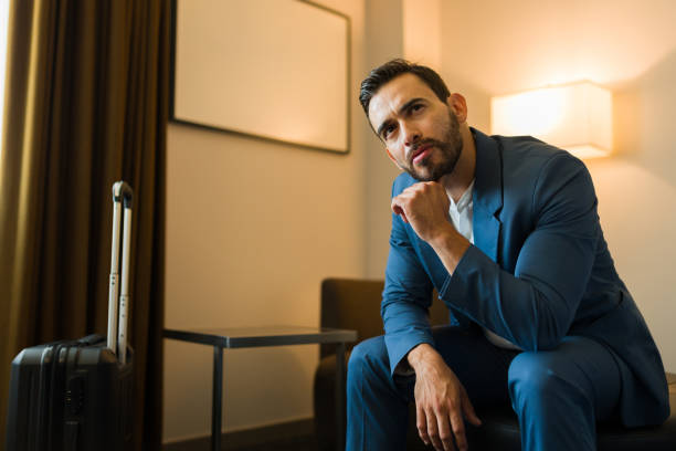 istock Attractive businessman deep in thought while seated in his hotel room next to his suitcase 2160125164