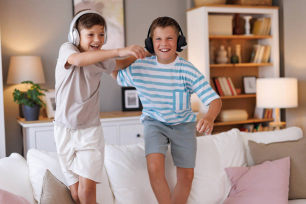 istock Boys dancing joyfully on a white sofa with headphones 2160125532