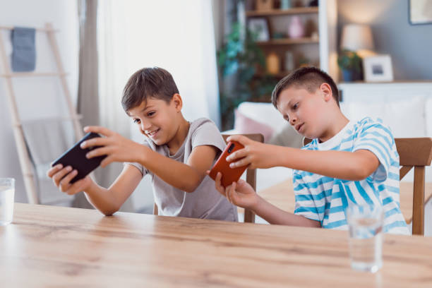 Boys play dominoes at home on bed and are having fun. Older brother teaches younger brother to play dominoes. Leisure game