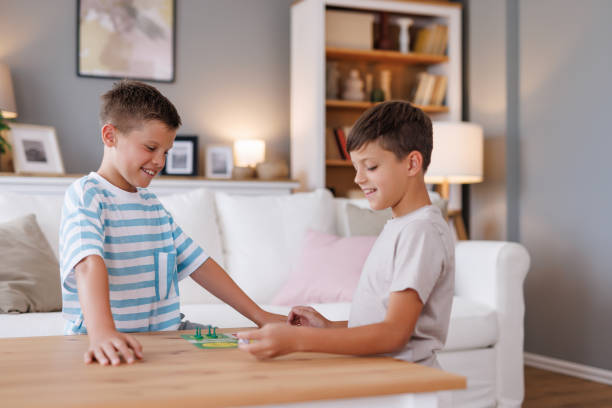 Two children delightedly playing a board game, sharing smiles and enjoyment in a living room filled with cozy décor and a warm atmosphere, reflecting their friendship and fun.