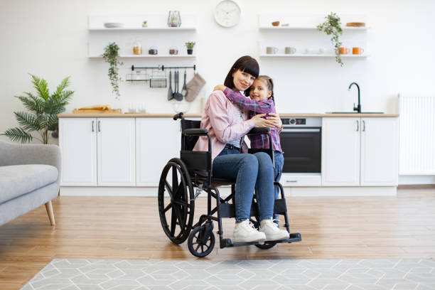 istock Mother in wheelchair hugging daughter in modern kitchen 2160132174