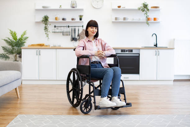 istock Woman in wheelchair sitting in modern kitchen interior 2160132178