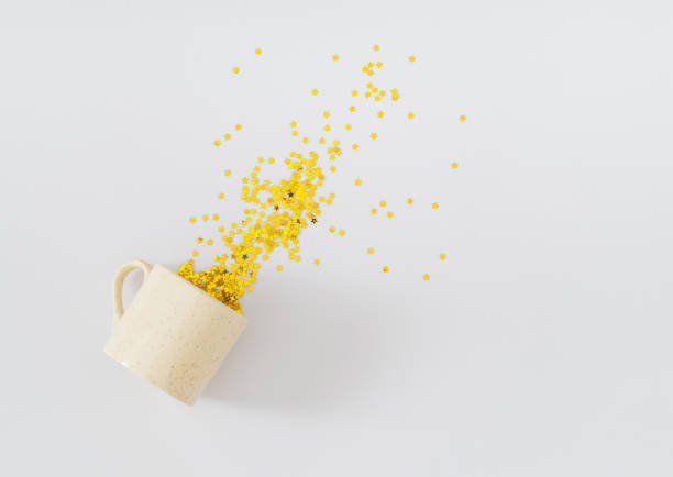 Creative layout made with coffee cup and golden glitter stars confetti on white background. Festive holiday backdrop. Minimal coffee party concept. Flat lay.