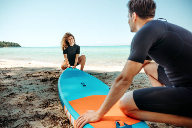 istock Young athletic couple with paddle board on beach 2160139704