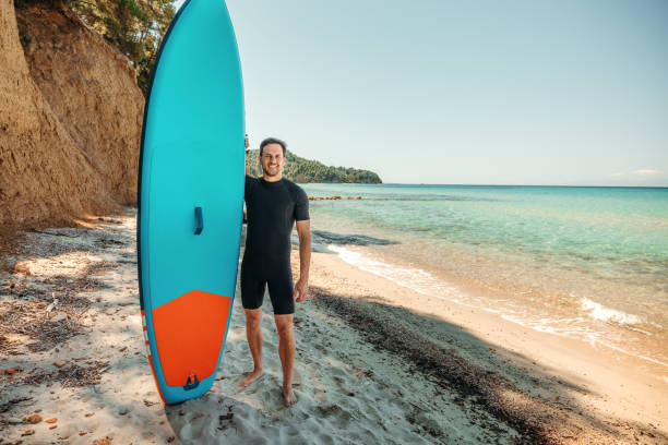 istock Young handsome athletic man with SUP board posing for a shot at the beach 2160139836