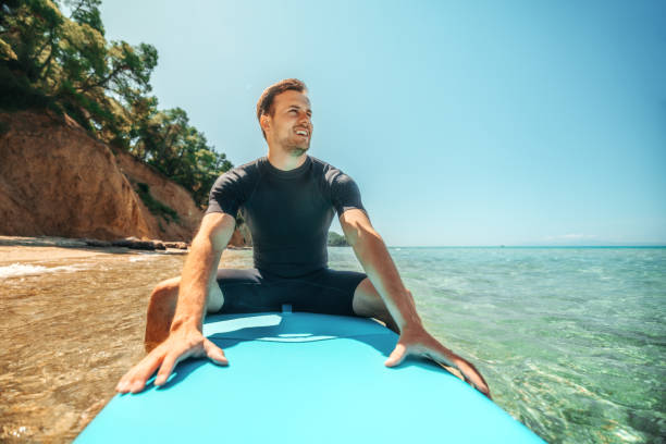 istock Man sitting on paddle board while enjoying day at the sea 2160139913
