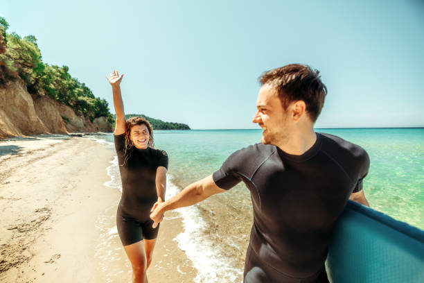 istock Young couple running on a beach while carrying sup board 2160139958