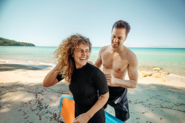 istock Young beautiful couple getting ready for paddle boarding at the beach 2160140006