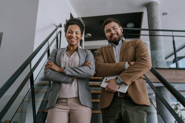 istock Two business professionals standing on a staircase in an office building 2160143448