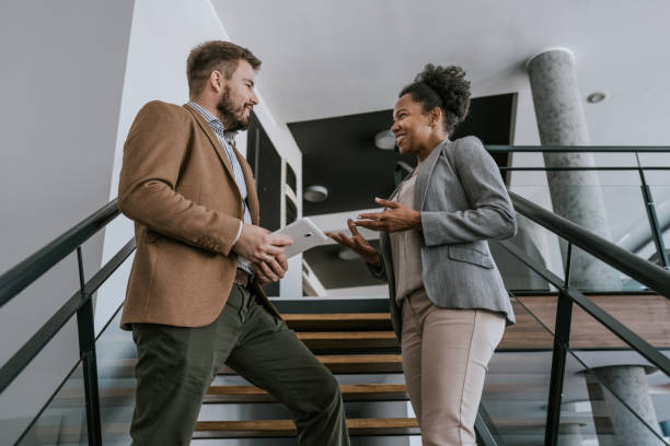 istock Business professionals discuss project details on modern office staircase 2160143472