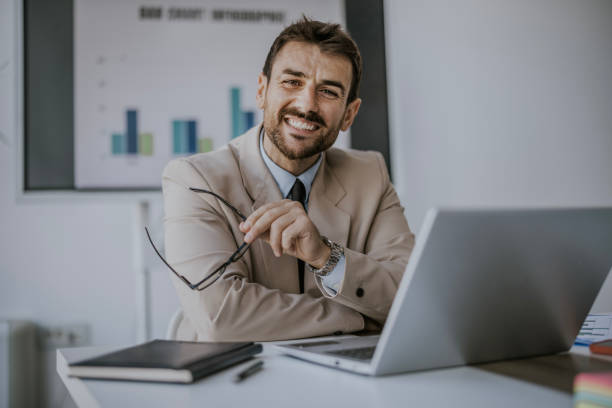 istock Smiling businessman working at a desk with a laptop 2160144333