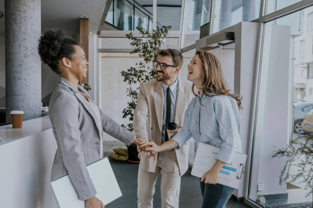 istock Business professionals shaking hands and laughing in modern office building 2160144446