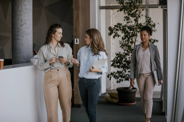 istock Three business professionals walking and talking in a modern office building 2160144583