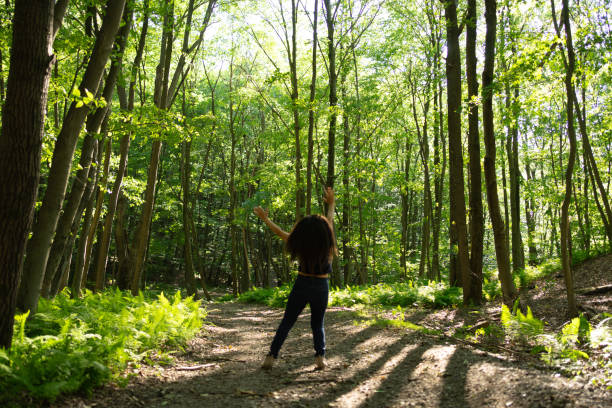 Una mujer disfrutando el bosque con los brazos abiertos