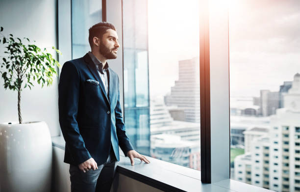 istock Office, thinking and businessman at window with vision, insight or decision for property developer in city. real estate agent, entrepreneur or man with business plan, inspiration or ideas in urban real estate 2160148025