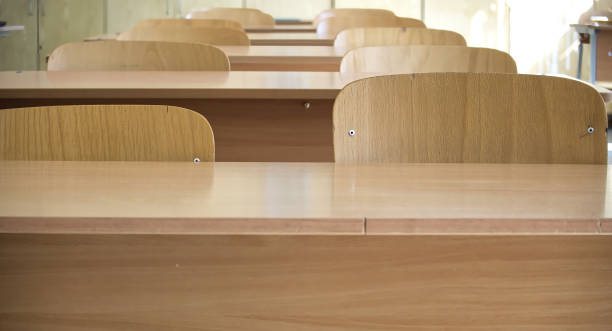 istock Empty classroom with wooden desks and chairs in sunlight 2160175878