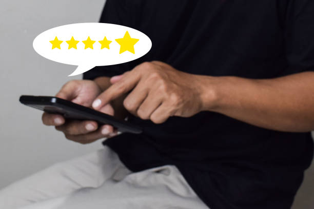 istock View of Customer hand pressing on smartphone screen with gold five star rating feedback icon 2160176971