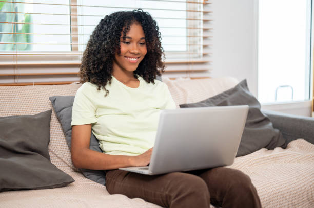 istock A happy young Black woman is working on her laptop computer on a couch at home. 2160182084