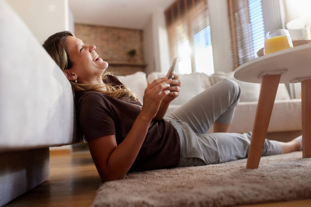 istock Cheerful woman using mobile phone on carpet at home. 2160190891