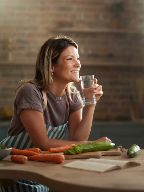 istock Happy woman day dreaming while drinking water in the kitchen. 2160191289