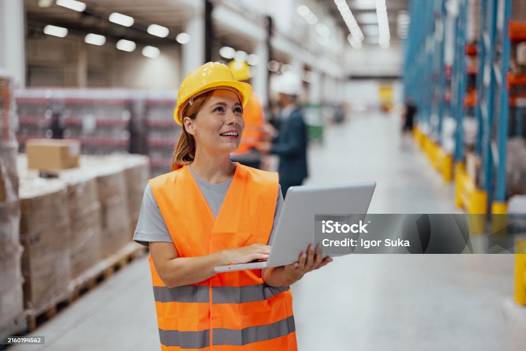 Pracownica korzystająca z laptopa podczas pracy w magazynie dystrybucyjnym - Zbiór zdjęć royalty-free (20-24 lata) Pracownica korzystająca z laptopa podczas pracy w magazynie dystrybucyjnym - Zbiór zdjęć royalty-free (20-24 lata)