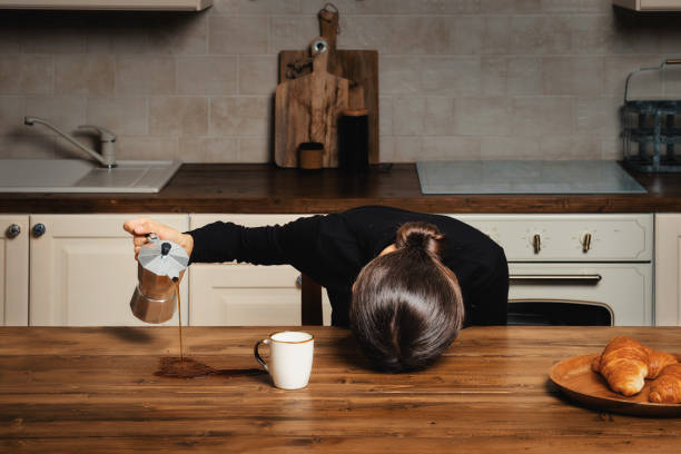 Sleepy woman spilling coffee on the table