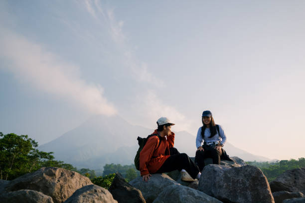 istock Two Friends Resting On Large Rock with Mount Merapi at the Backgroud 2160200912