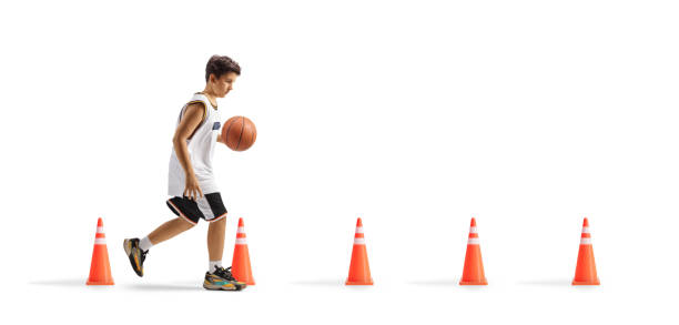 Boy leading a basketball and training with obstacle cones isolated on white background
