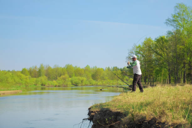 Fisherman throwing the bait with a spinning rod. Outdoor weekend activity. Photo with shallow depth of field taken at wide open aperture.