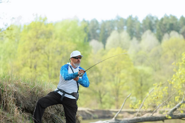 Fisherman trying to do a perfect cast, throwing lure. Spining fishing, angling, catching fish. Hobby and vacation. Photo with shallow depth of field taken at wide open aperture.