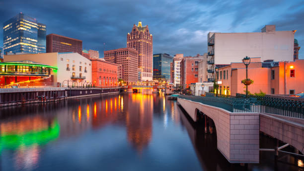 Cityscape image of downtown Milwaukee, Wisconsin, USA with reflection of the skyline in Milwaukee River at summer sunset.