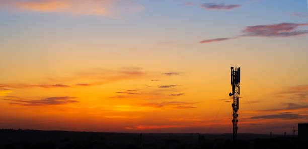 Silhouette of a telecommunications tower against a vibrant sunset sky.