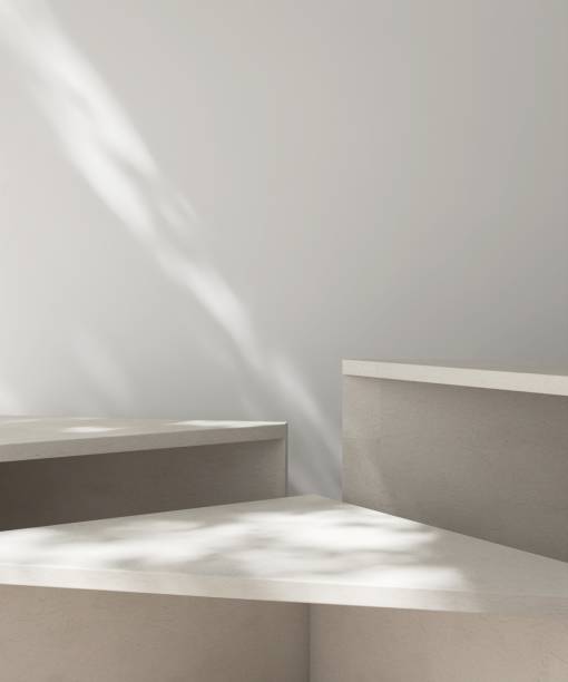 Three modern, minimal geometric cream pedestal podium in dapple sunlight, shadow on white wall