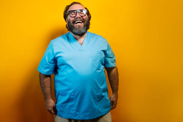 Friendly doctor smiling in blue coat on yellow background.