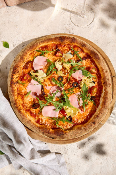 istock Summer Delight Mortadella and Artichoke Pizza with Arugula in Sunlight and Shadow 2160217849